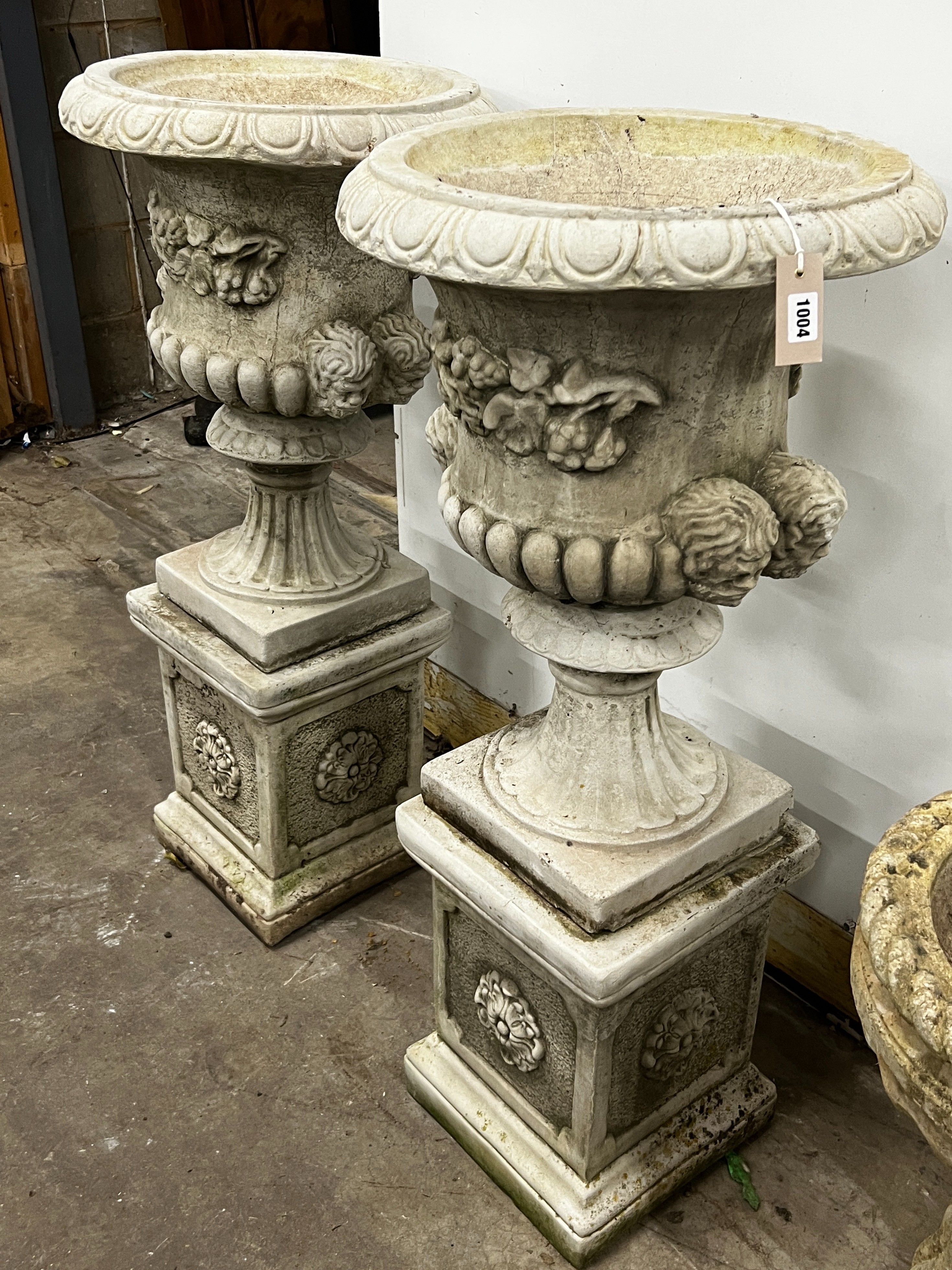 A pair of reconstituted stone campana garden urns on square pedestals, diameter 49cm, height 108cm